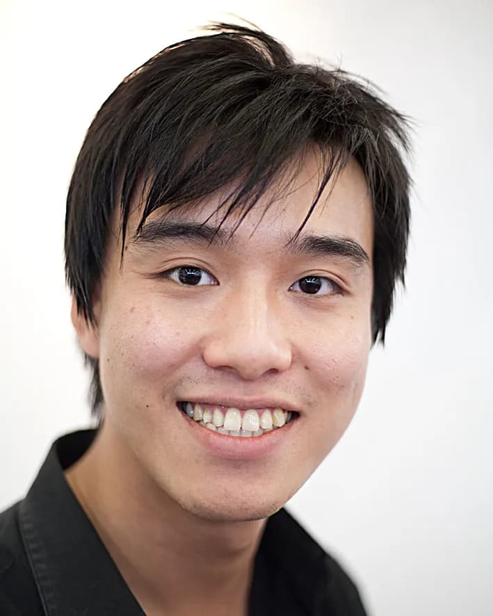 Professional headshot of a man with a beard in a white button-up shirt and arms crossed