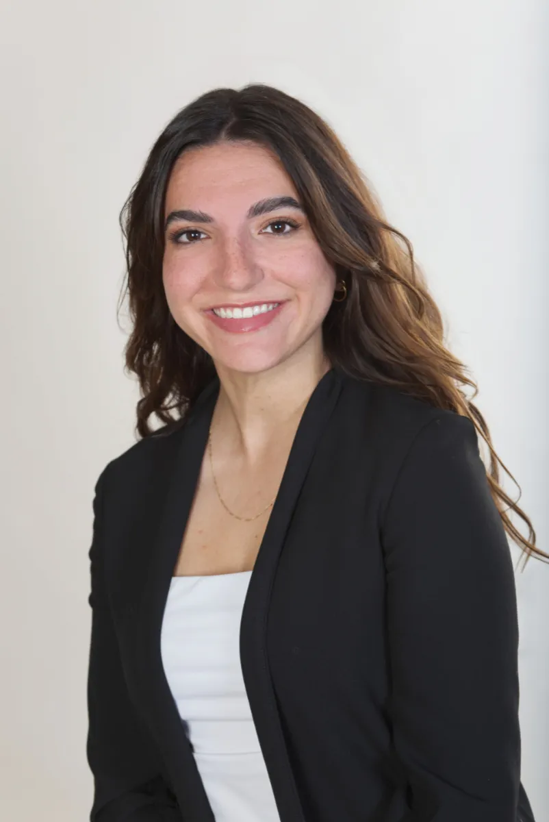 Professional headshot of a woman with brown hair in a black blazer and white top angled slightly