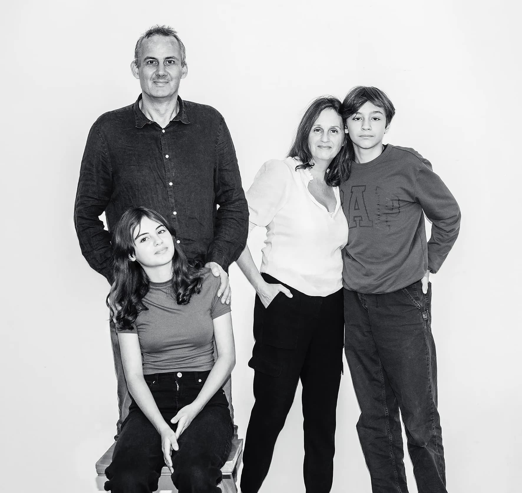 Candid family portrait of a family of four laughing together in a relaxed studio setting