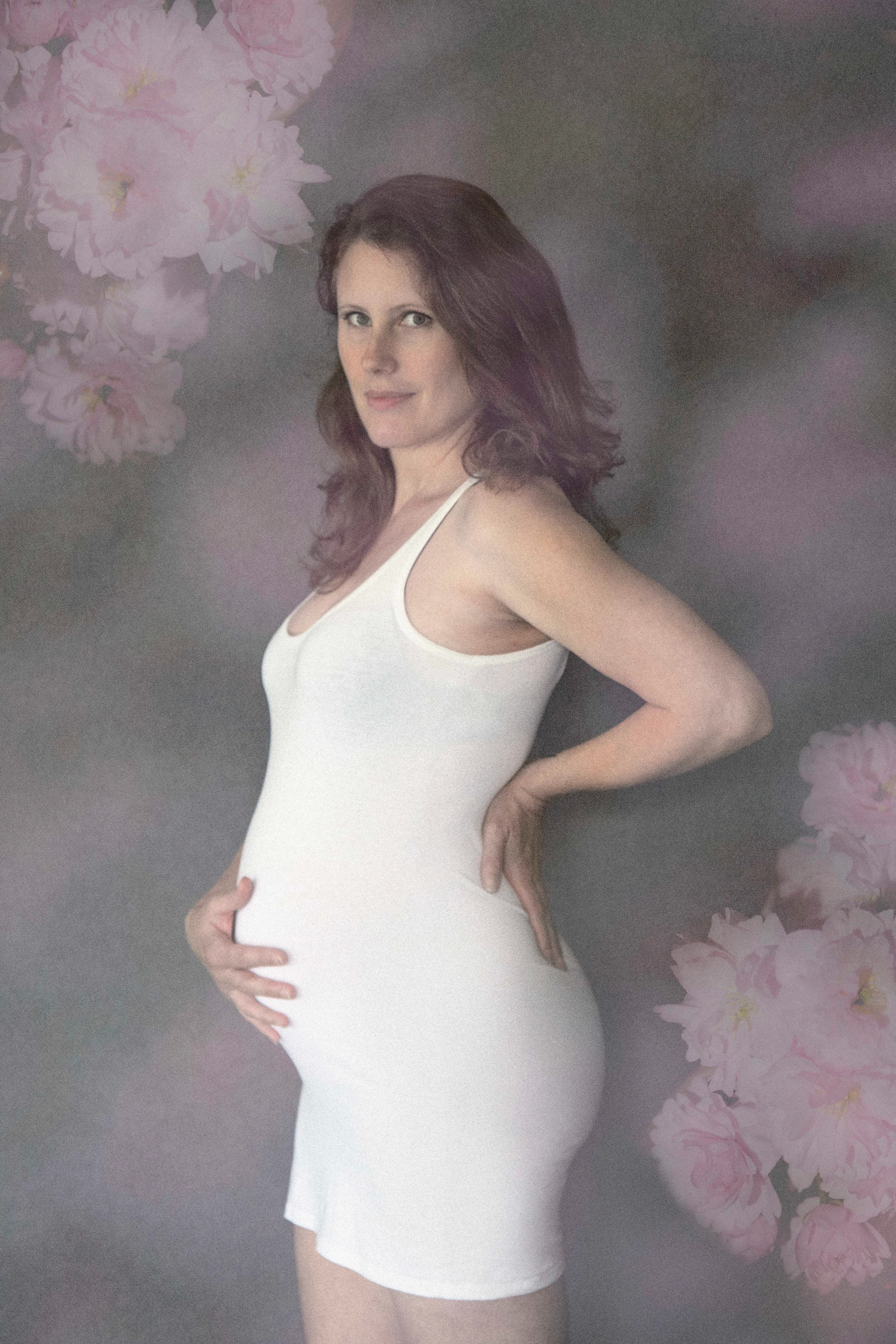 Tender maternity portrait of a daughter smiling while hugging her pregnant mothers baby bump