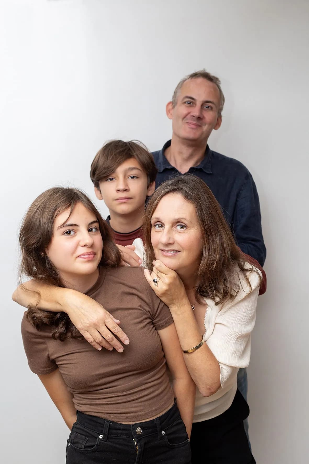 Studio family portrait of a family of four grouped together naturally on a white background