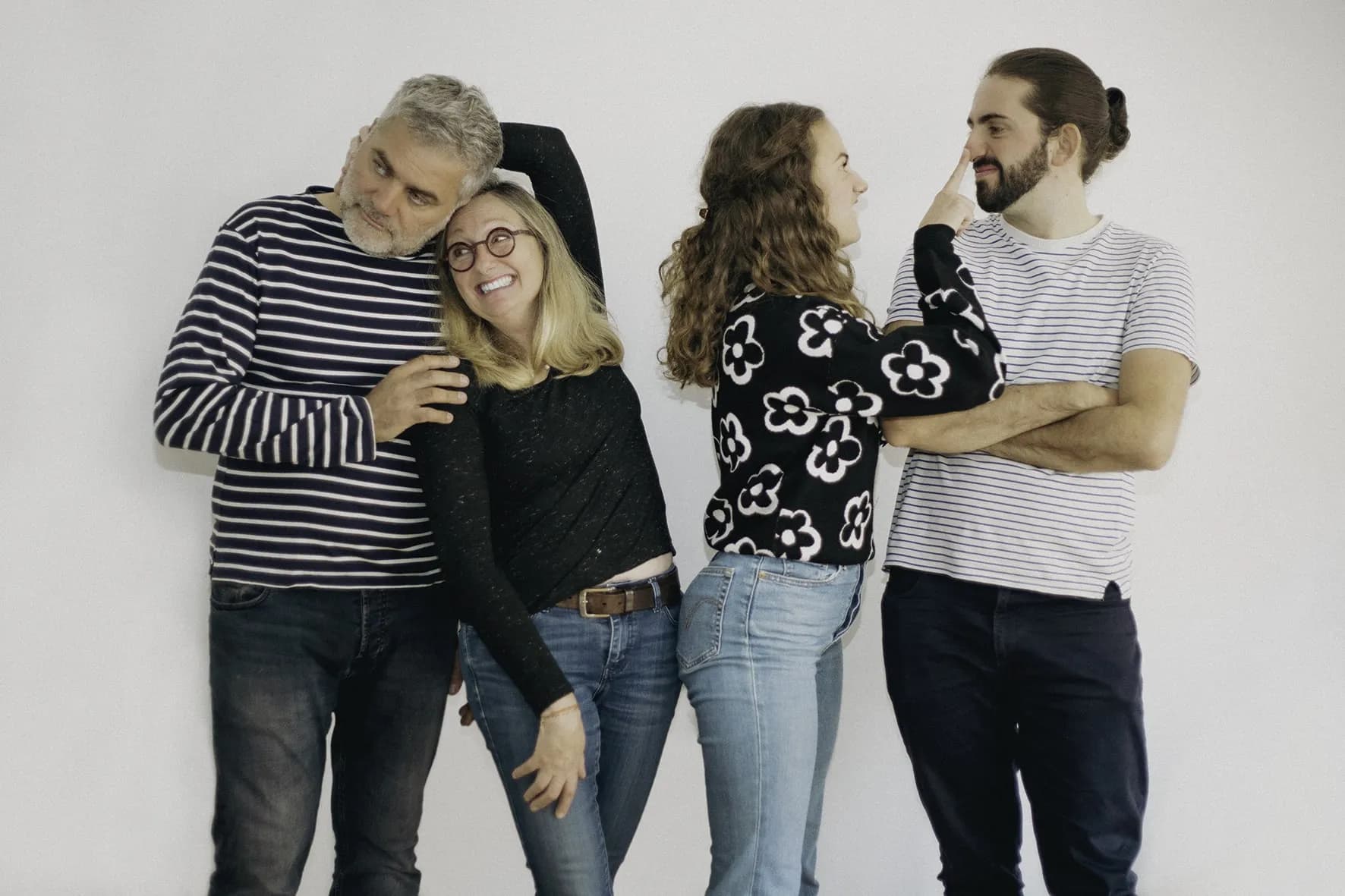 Candid family portrait of parents with grown children sharing a fun moment in studio